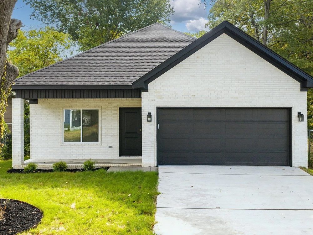 White painted brick ranch home with dark trim and garage door