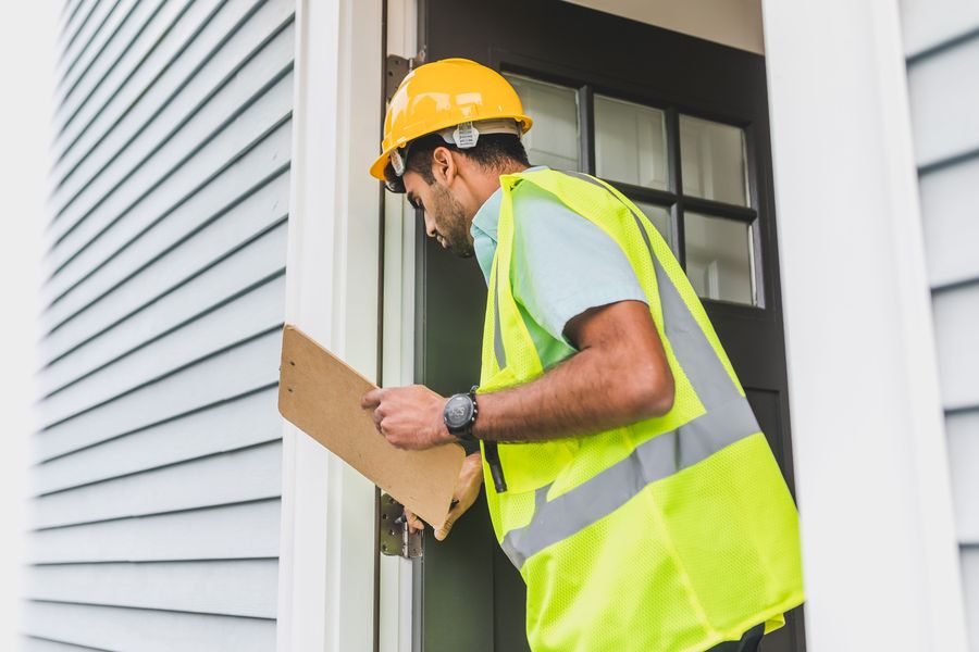 Contractor inspecting a home's siding during a repair visit